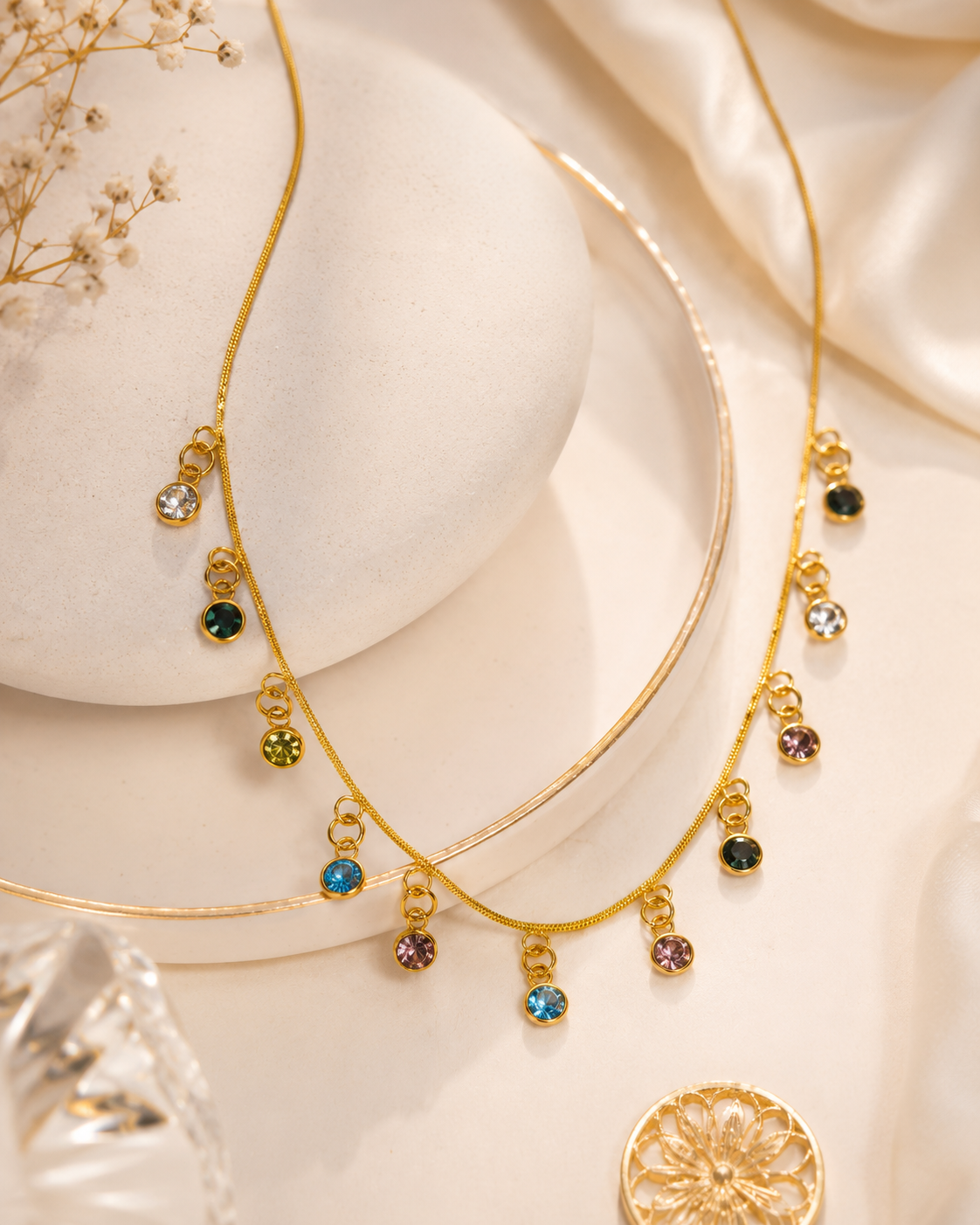 Gold necklace with colorful gemstones on a soft beige background